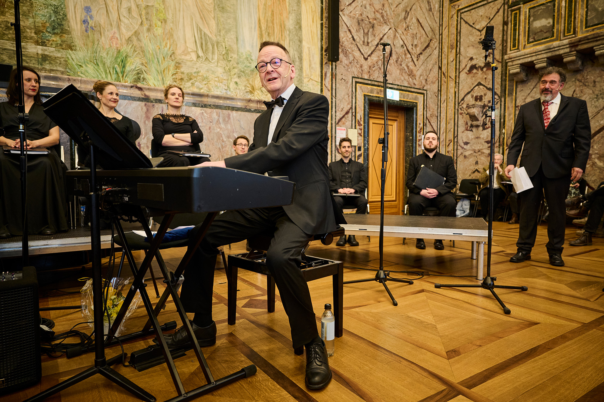 Rudolf Lutz sitzt am Klavier, im Hintergrund Jörg Frey